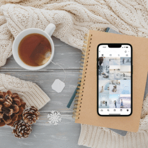 Plattläggning med kopp te, anteckningsbok och mobiltelefon på stickad filt – mysig vinterkänsla.